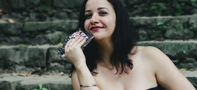 cartomante camilla carvalho sentada em uma escada segurando o baralho cigano